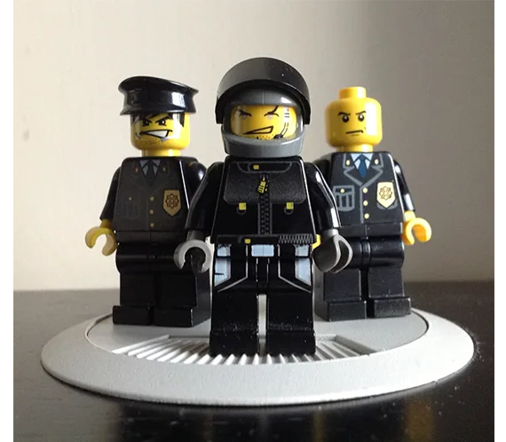 Three LEGO minifigure agents in black uniforms on a display stand